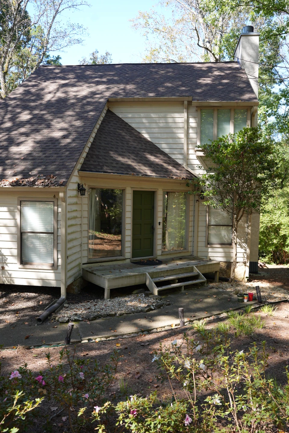A vertical view of a home's front entrance, chimney and surrounding garden