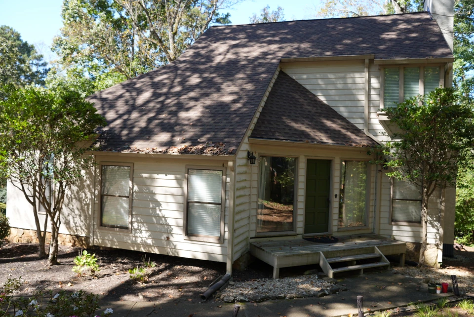 A home's green front door and wooden entry steps beneath a sloped roof